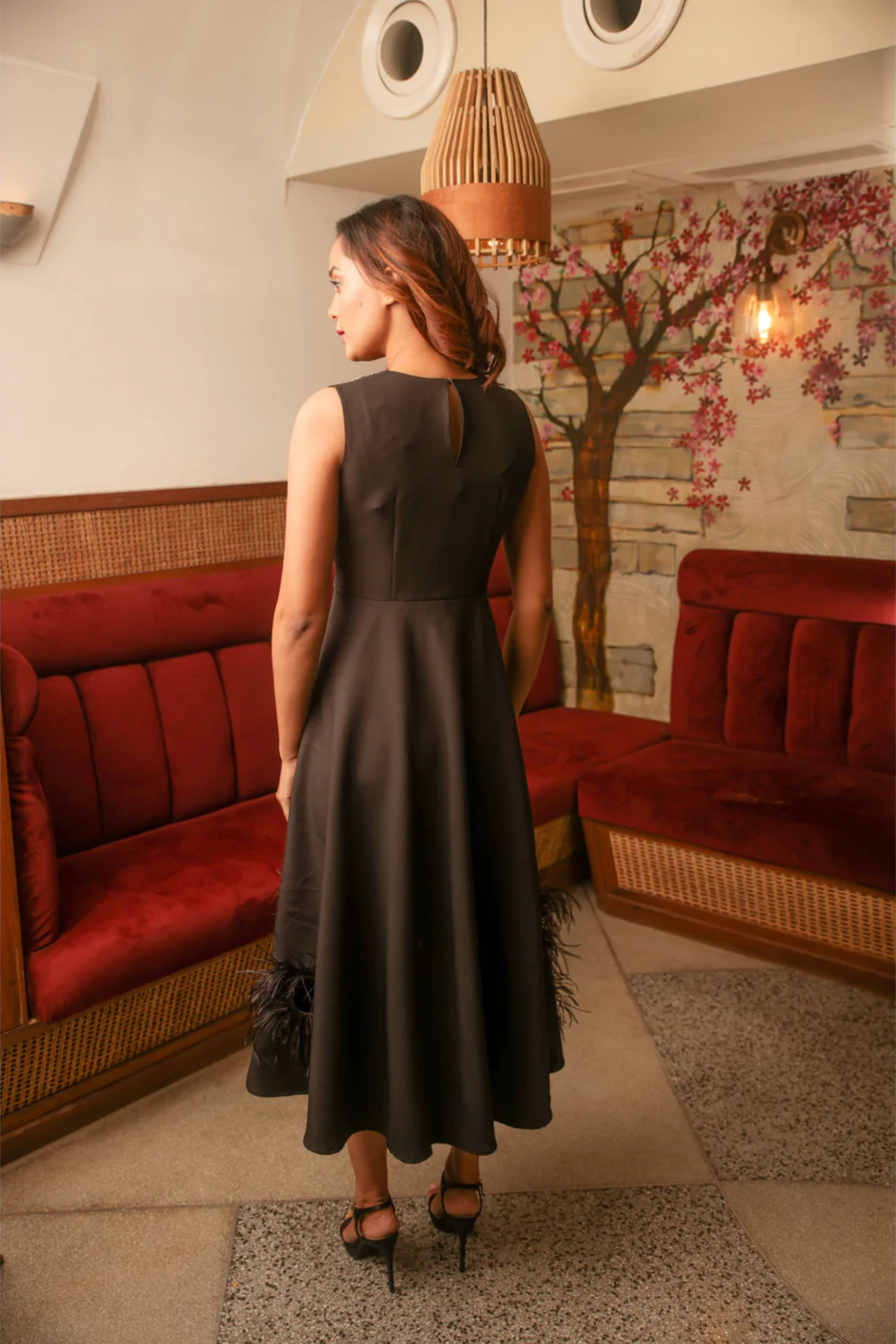 Black sleeveless long midi dress with stone embellishment on neckline and feather detailing.