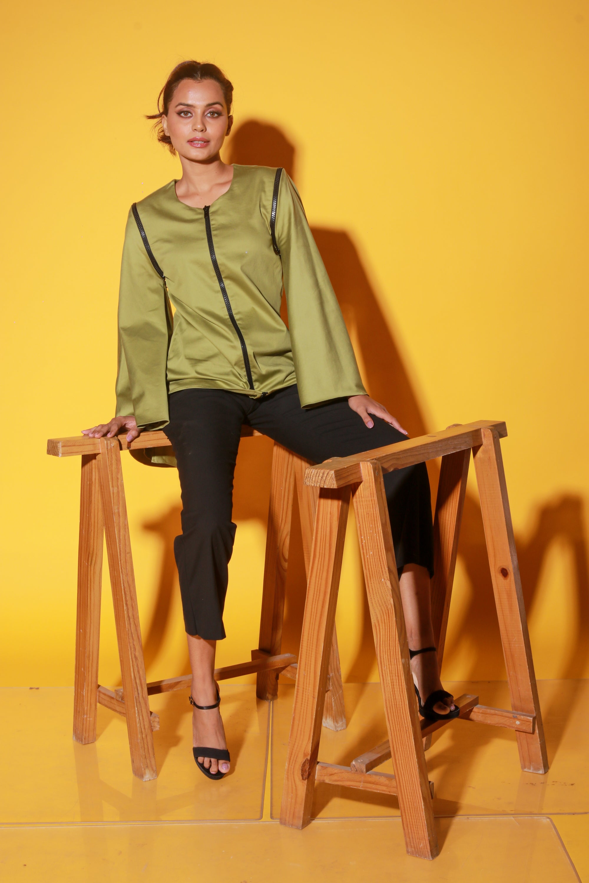 Moss green top features a zipper and asymmetric bell sleeves.