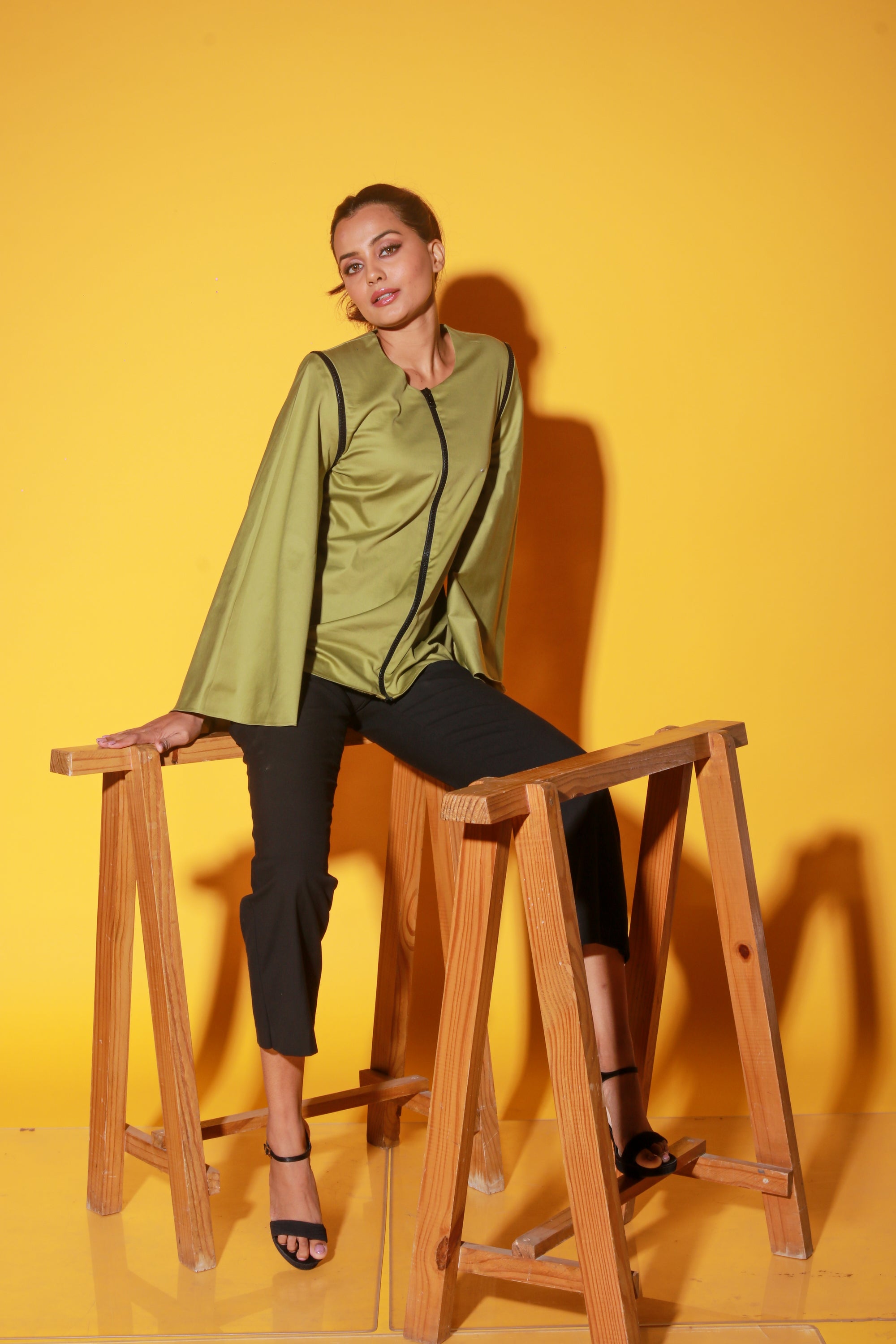 Moss green top features a zipper and asymmetric bell sleeves.