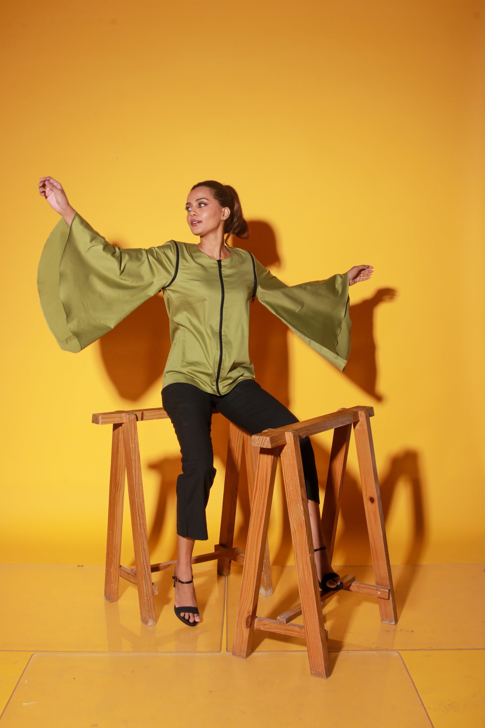 Moss green top features a zipper and asymmetric bell sleeves.