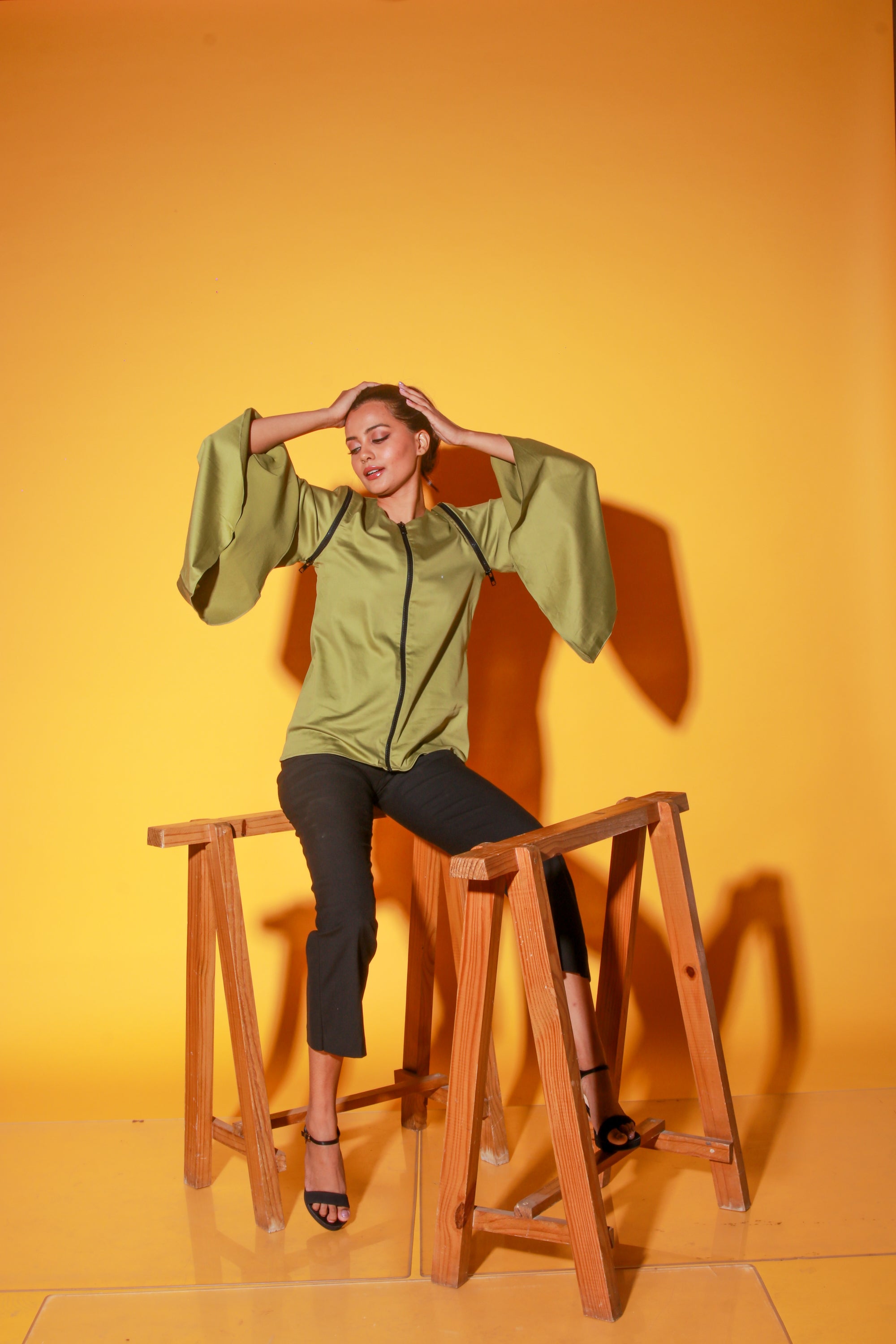 Moss green top features a zipper and asymmetric bell sleeves.