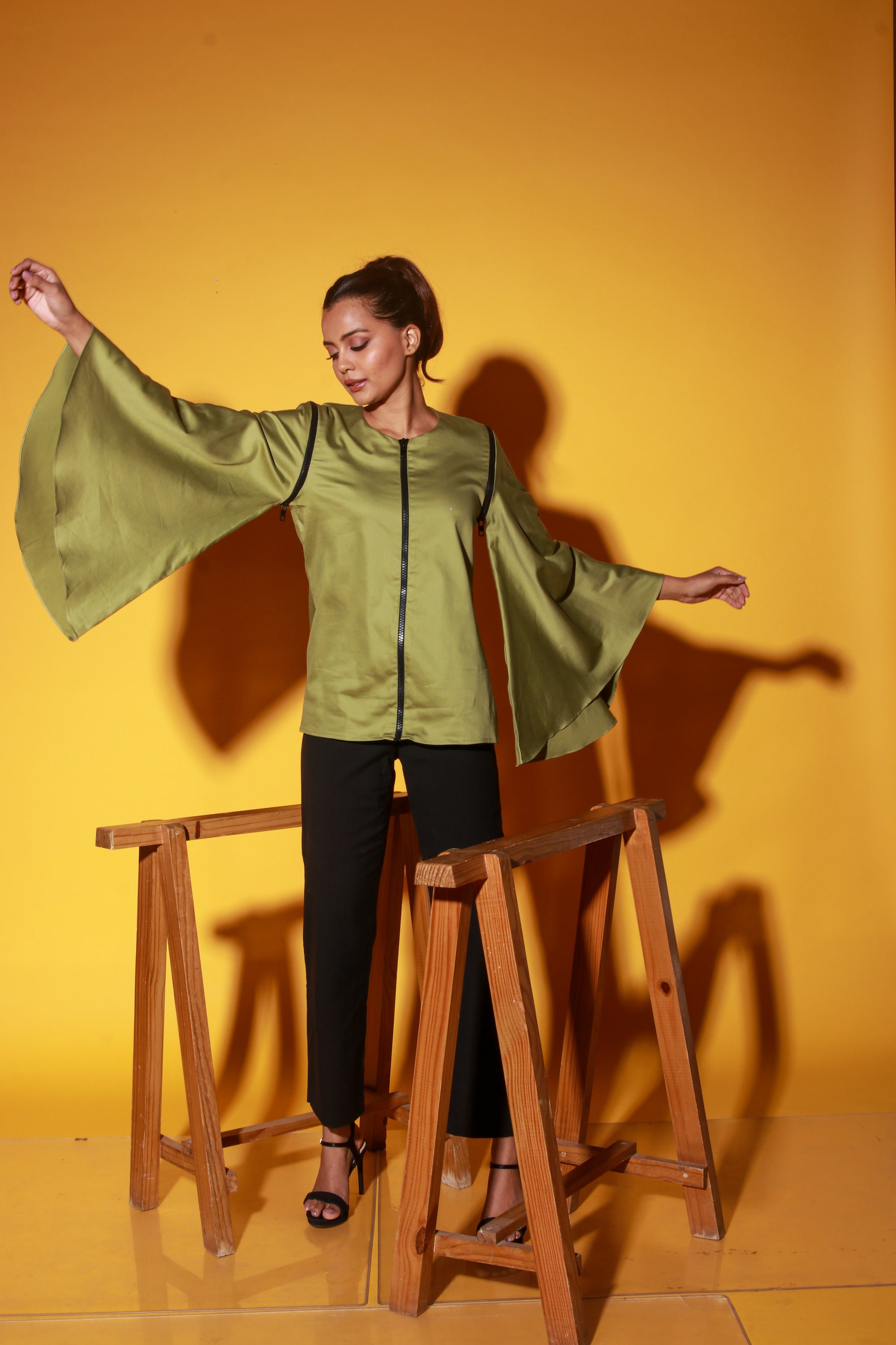 Moss green top features a zipper and asymmetric bell sleeves.