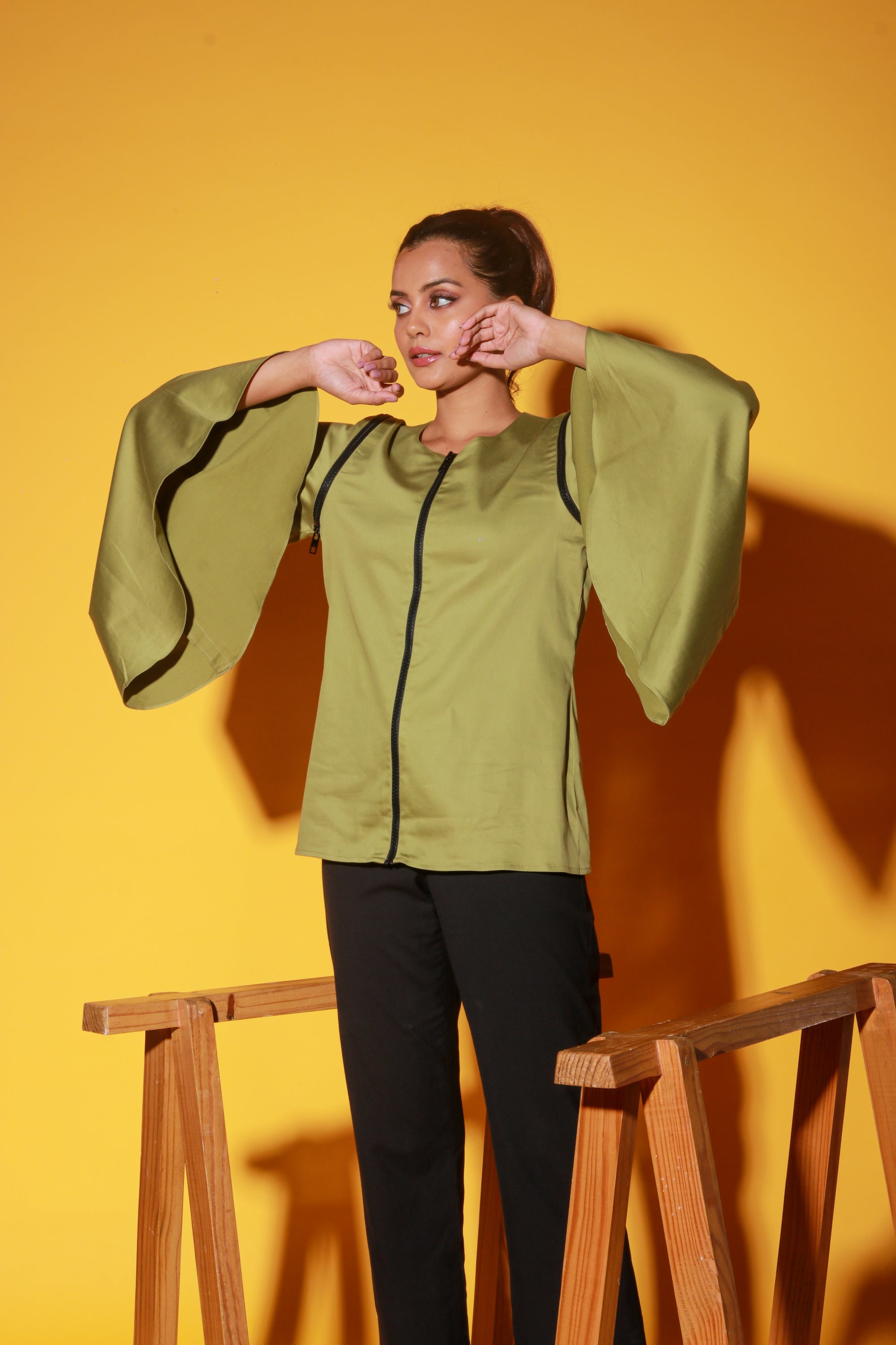 Moss green top features a zipper and asymmetric bell sleeves.
