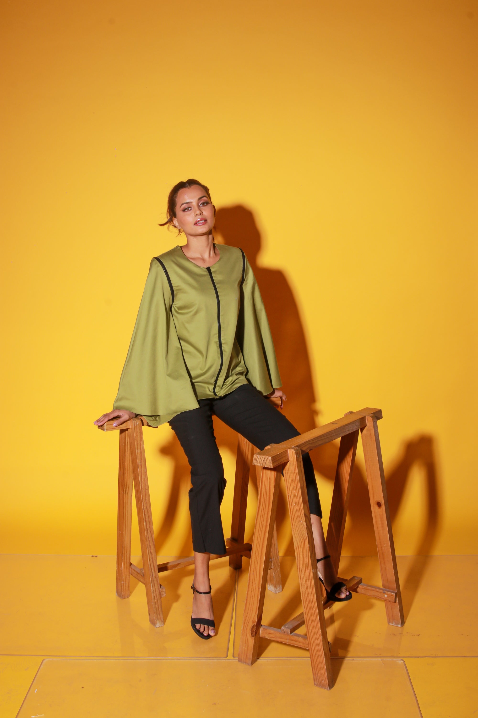 Moss green top features a zipper and asymmetric bell sleeves.