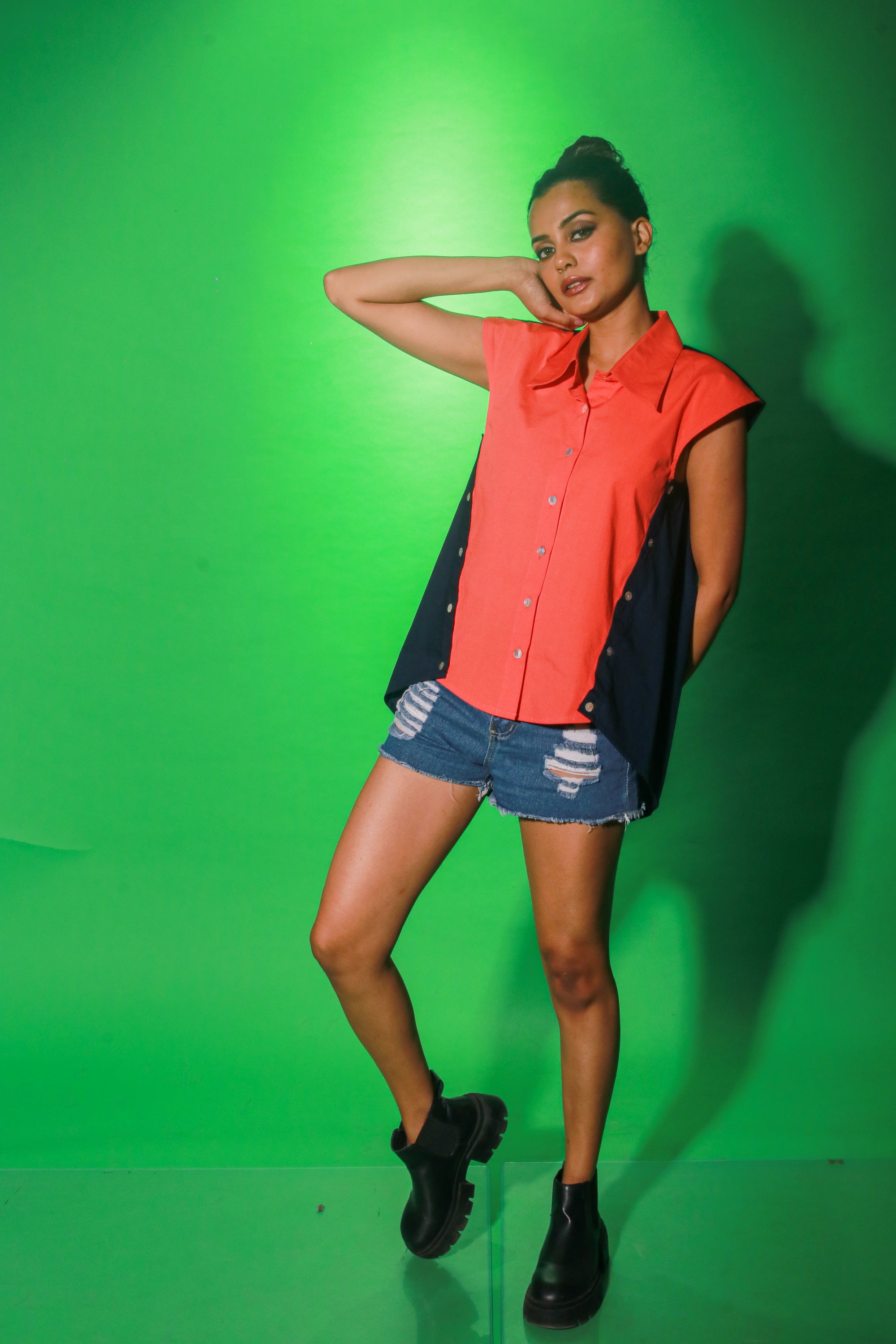 Coral and navy blue sleeveless top features collar and button detailing on both sides of the buttoned placket.