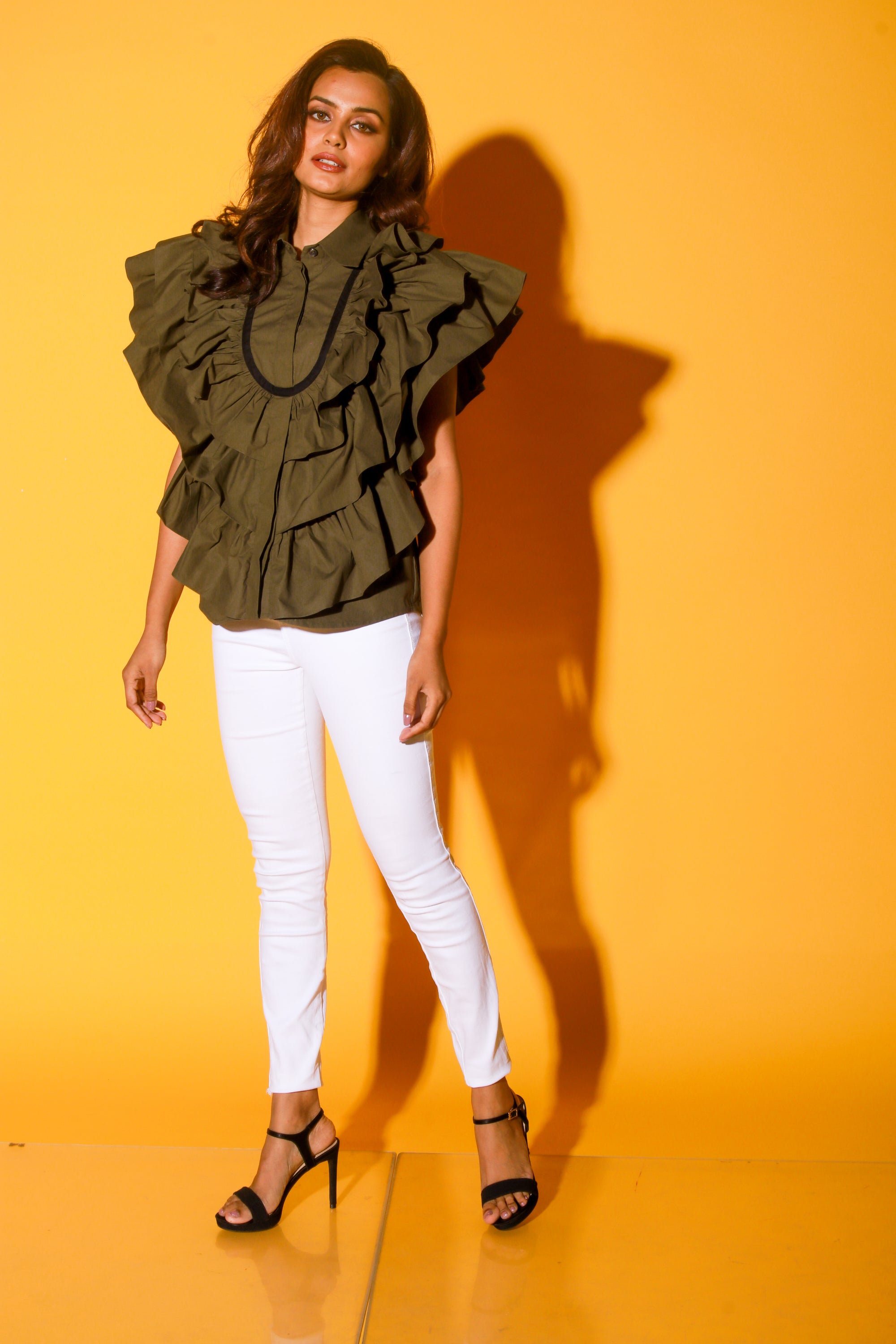 Olive green shirt features ruffles and black pipeing on the yoke.