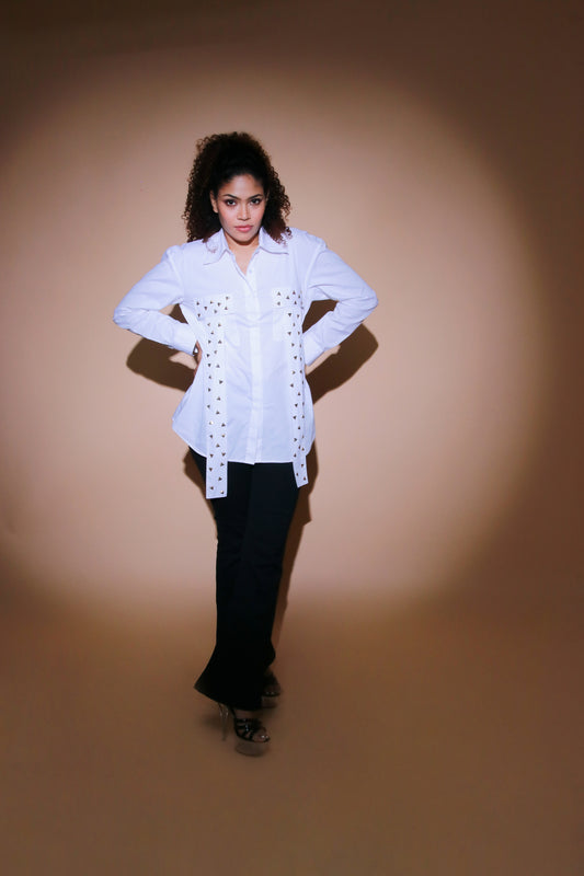 White shirt has drop shoulders, pockets with long strips, and golden embellishments on the pocket flap