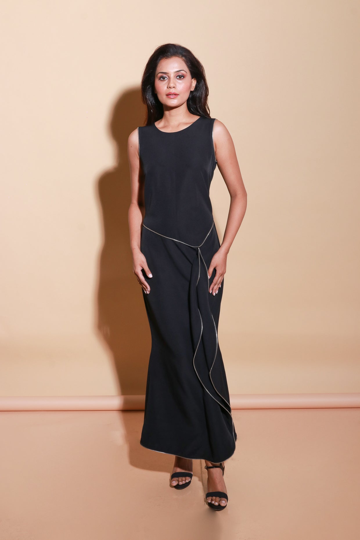 Sleeveless long black scuba dress with a zipper on the front and a side trail.