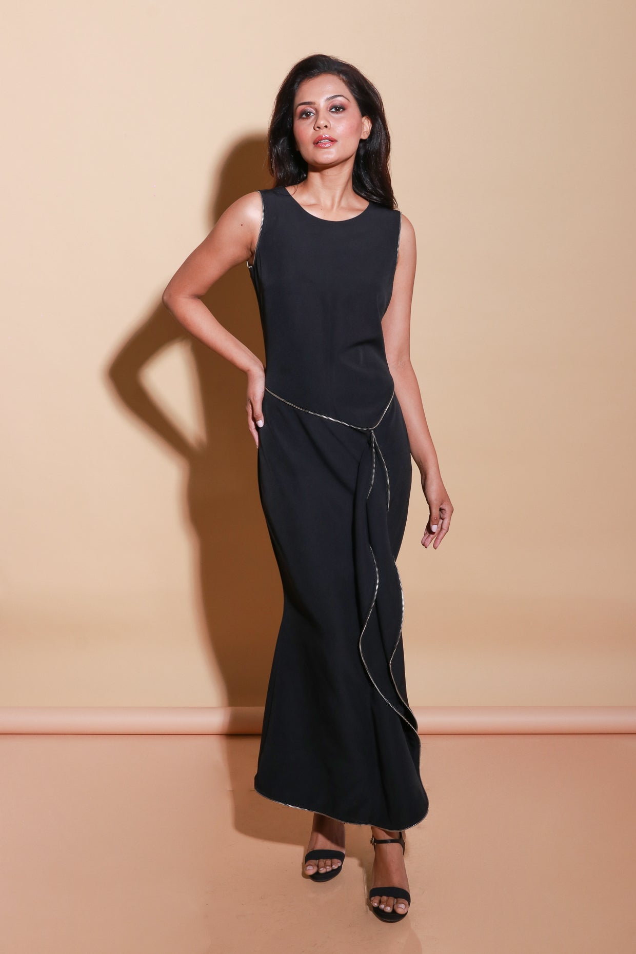 Sleeveless long black scuba dress with a zipper on the front and a side trail.