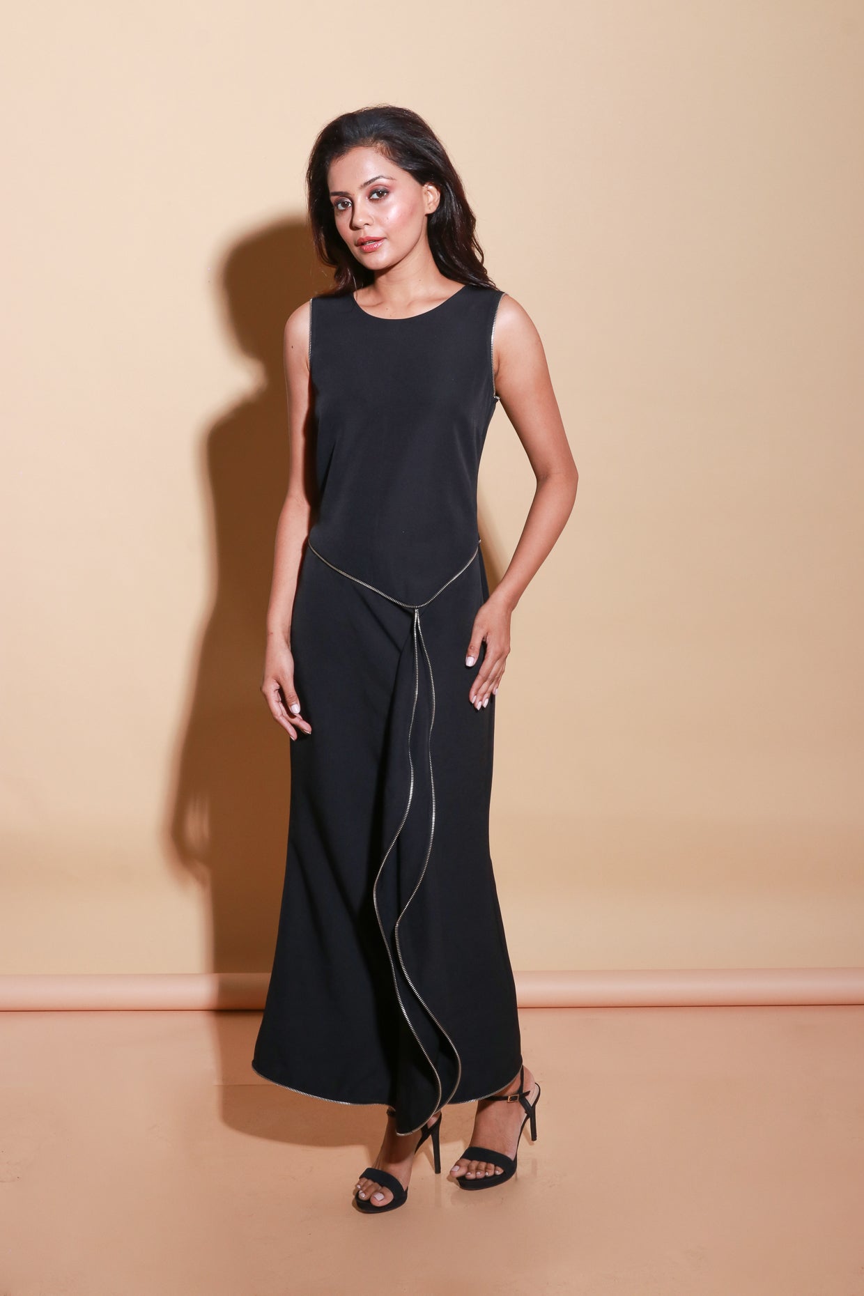 Sleeveless long black scuba dress with a zipper on the front and a side trail.