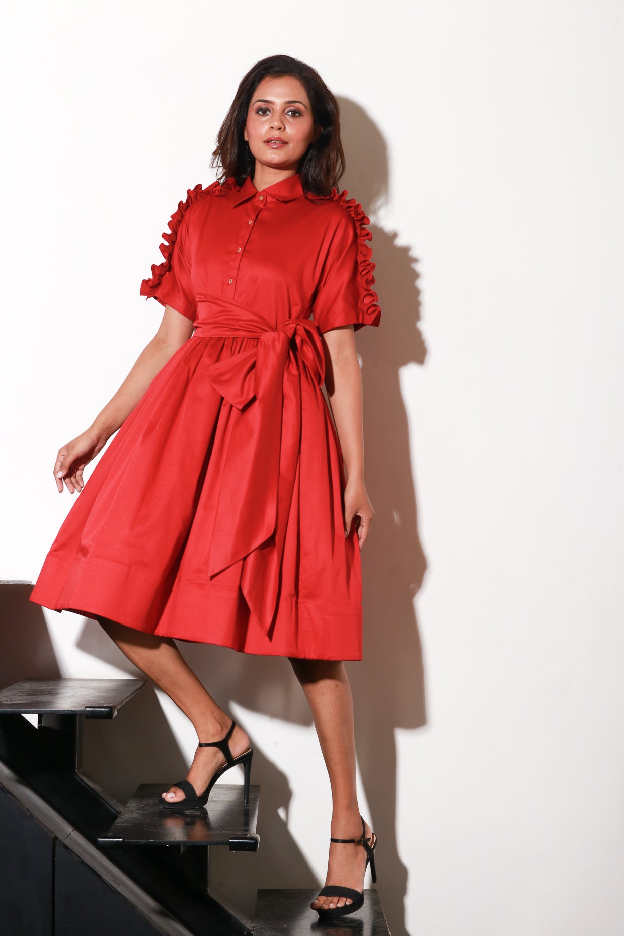 Red lady dress with waist flare and ruffle feature on shoulders and sleeves.
