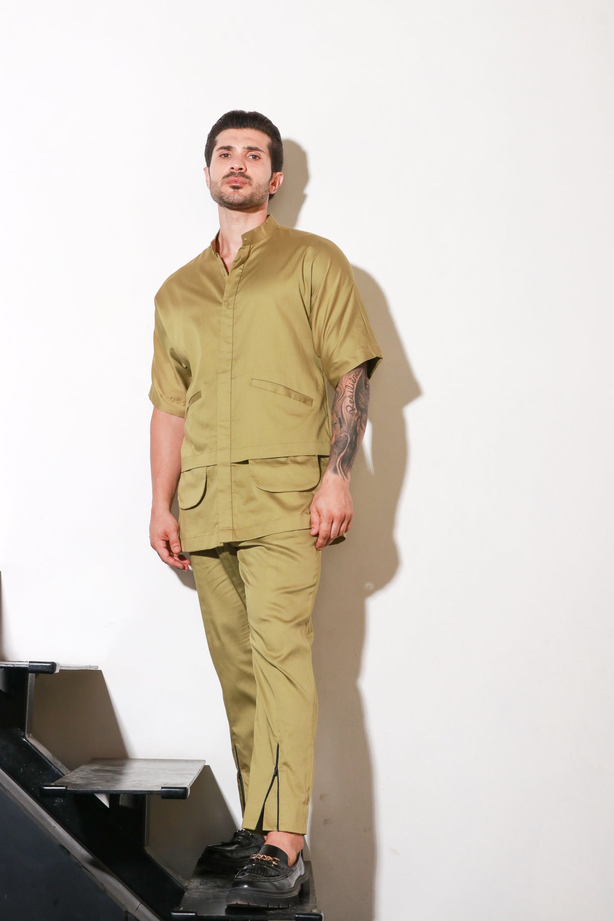 Green double layered shirt with pocket and flap feature paired with narrow pants with bottom zipper detailing.