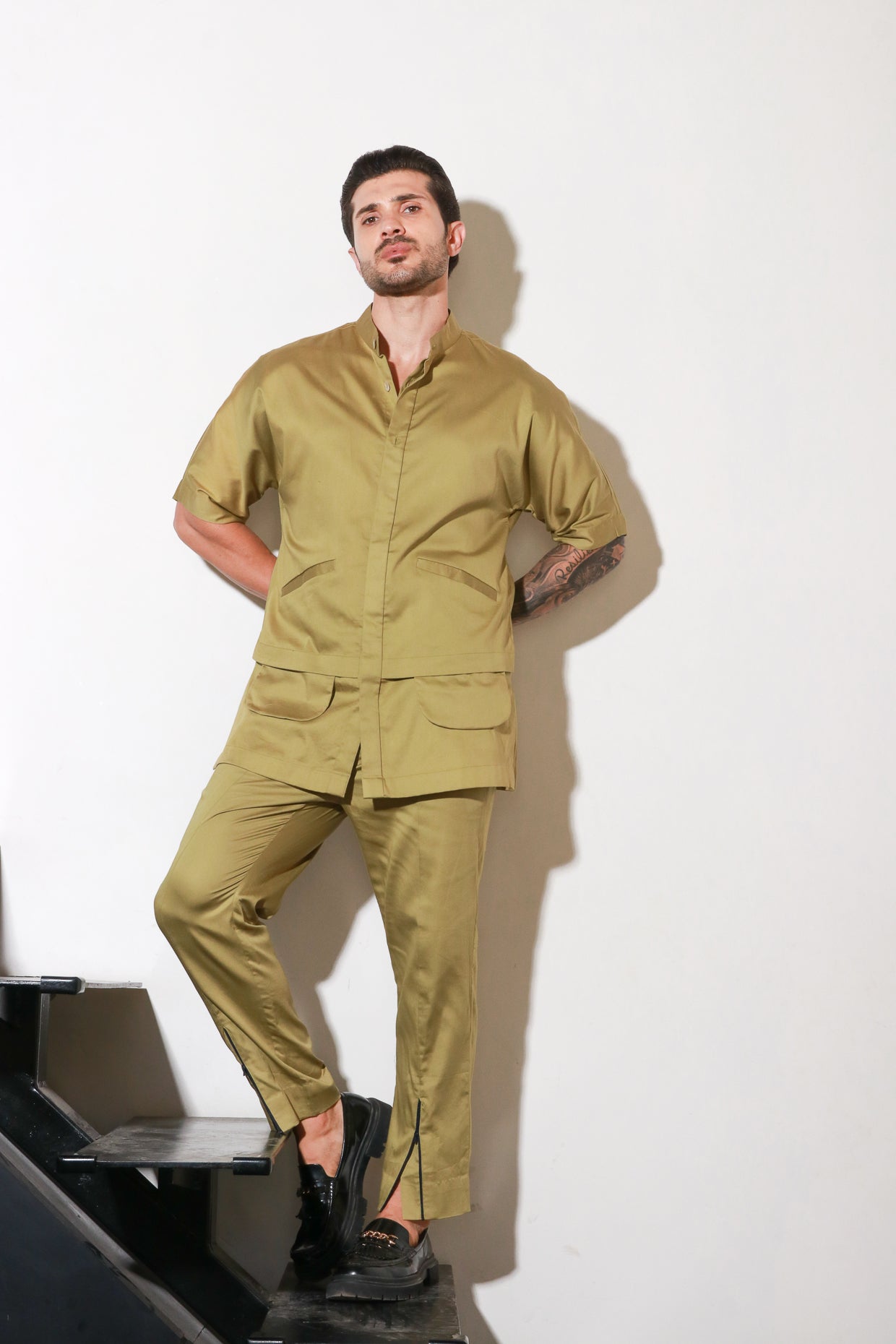 Green double layered shirt with pocket and flap feature paired with narrow pants with bottom zipper detailing.