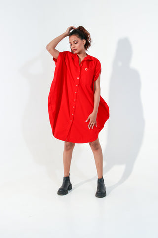 Red circle dress features one pocket & a golden eyelet.