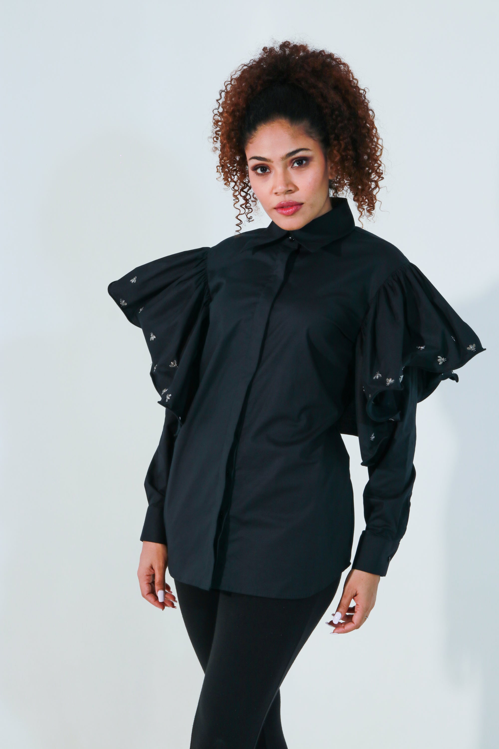 Black shirt features with bee embellishments and frill on the sleeves.