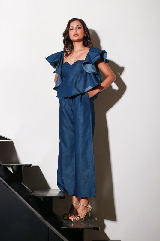 Denim jumpsuit with thick white stitching, bustier and frill feature around the neckline and shoulders.