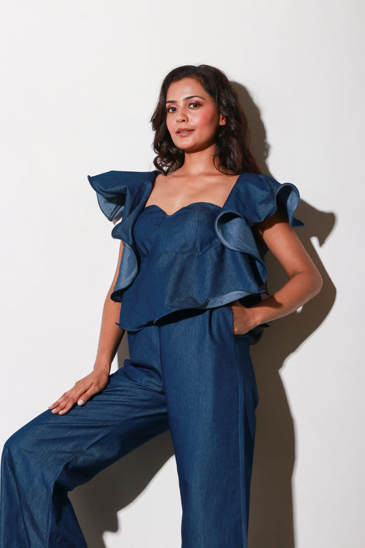 Denim jumpsuit with thick white stitching, bustier and frill feature around the neckline and shoulders.