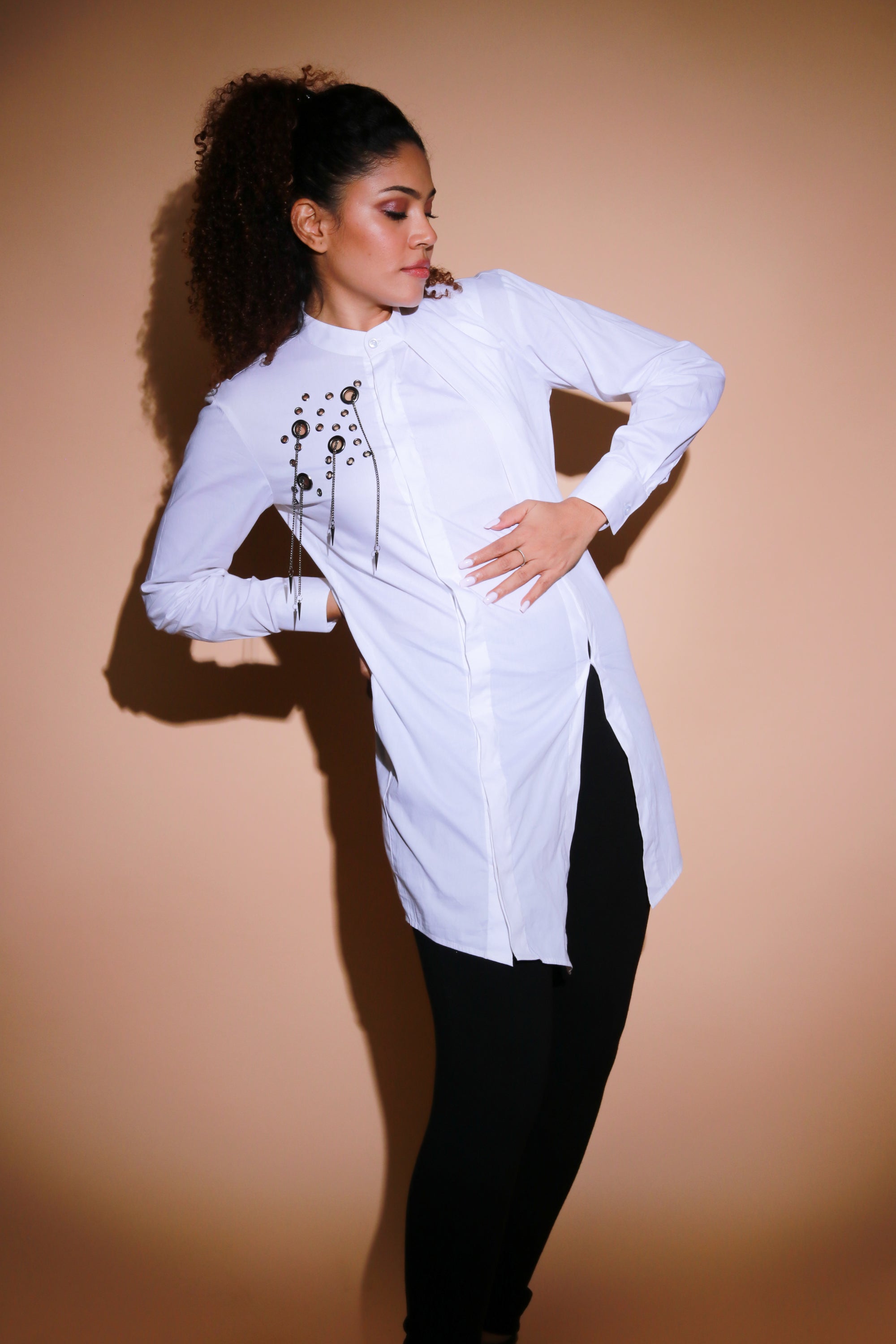 White top features an open side flap and eyelet and chains embellishment.