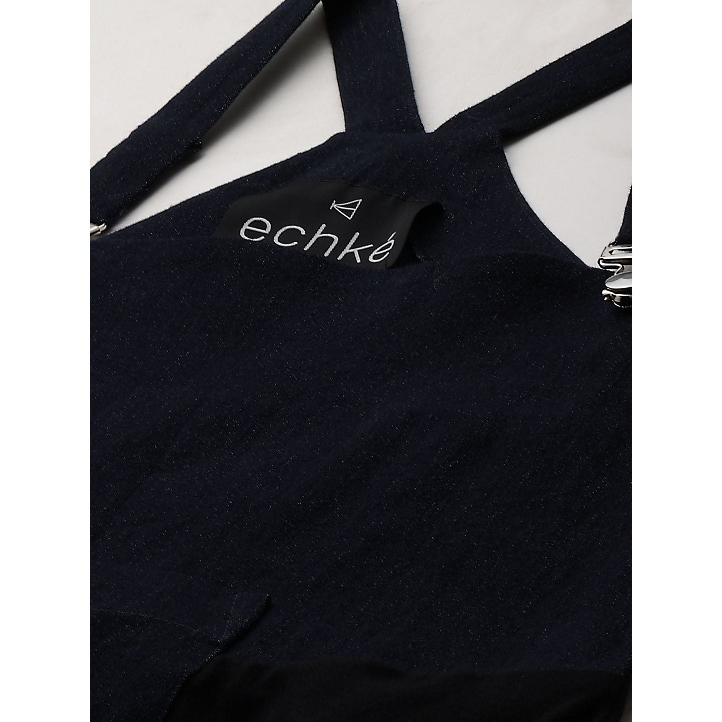 Denim dungaree dress features an assymmetric hemline.